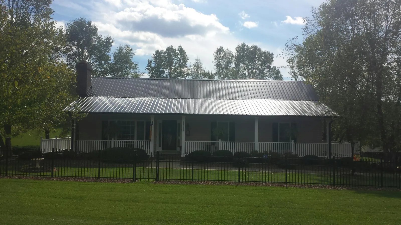 Gray metal roof on a brick ranch with a full width front porch — Gutter Guard Installation work by our crew in Riverside